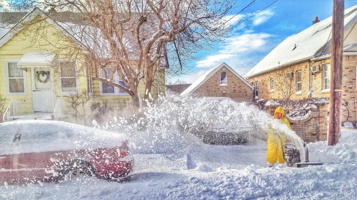Snøfreser som rydder snø foran et hus etter snøfall